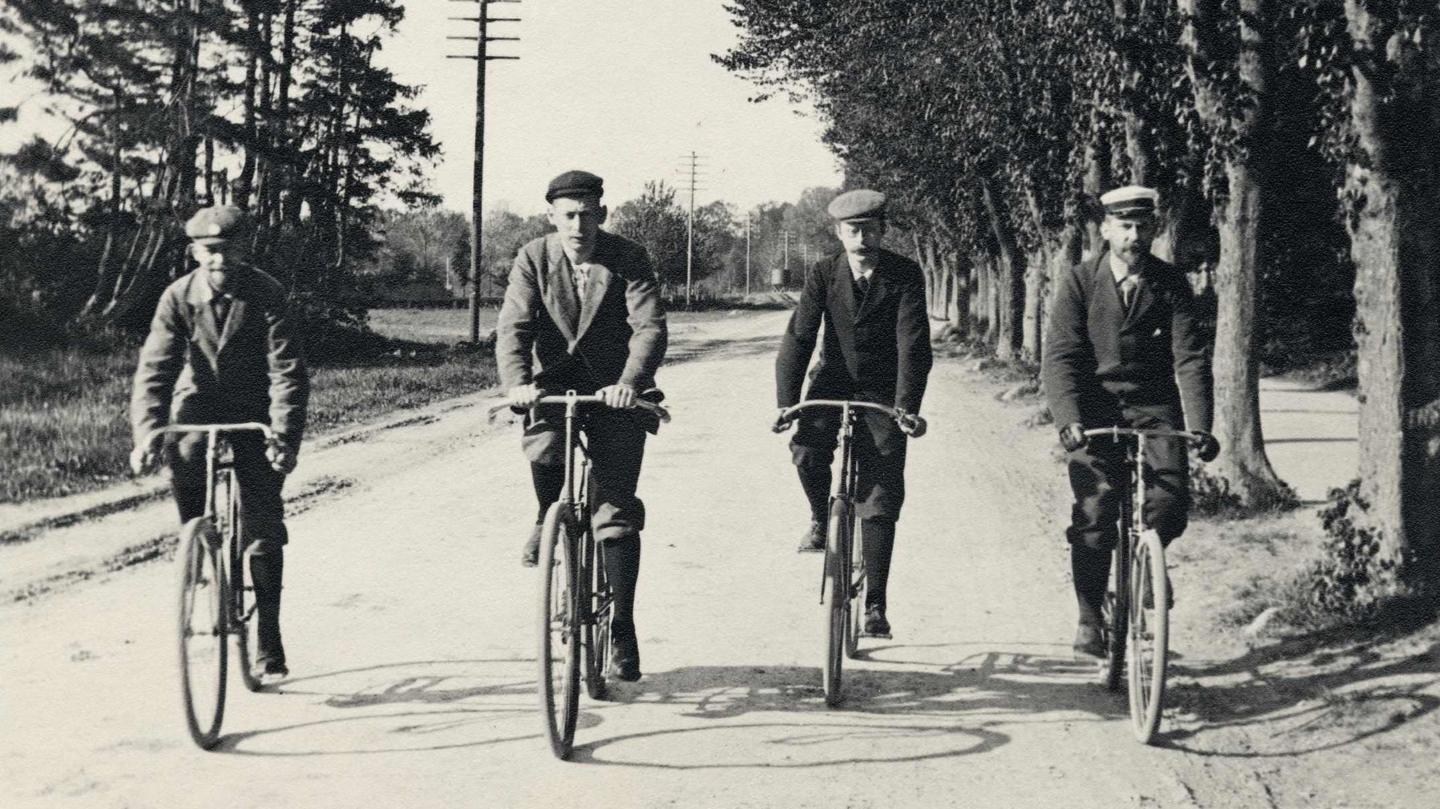 Fire cyklister på vej mod nord ad Strandvejen ud for Charlottenlund Skov. Datering: 1897. Fotograf: Peter Elfelt.