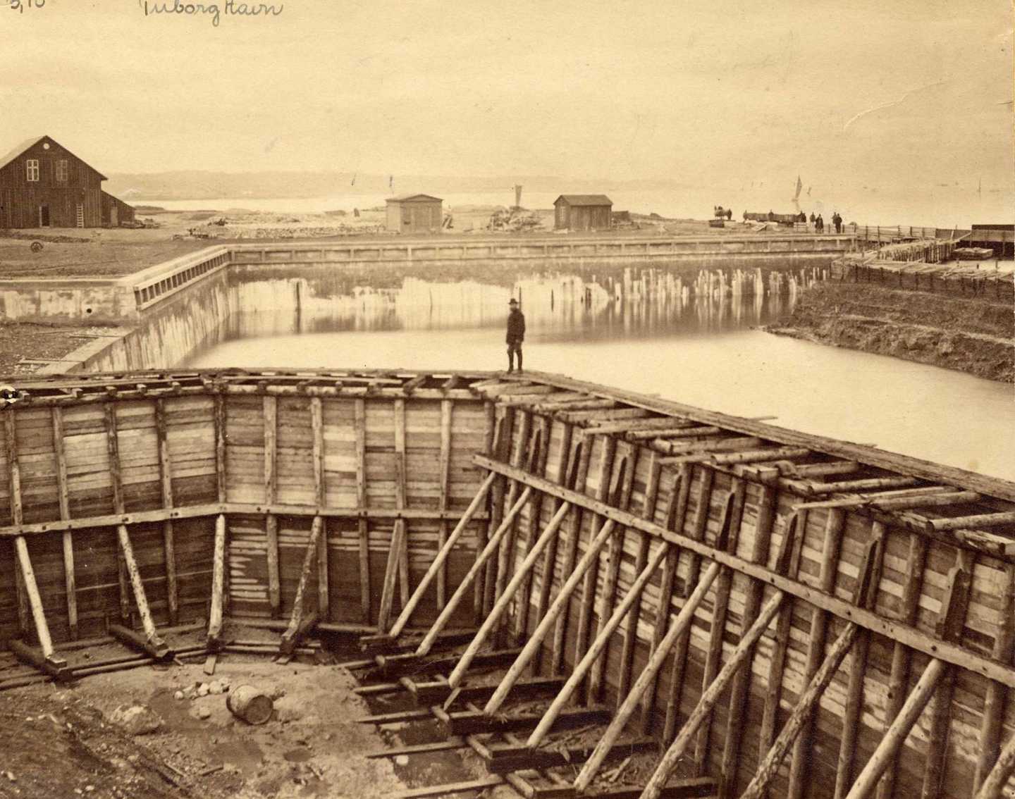 Trækonstruktion inddæmmer vandet i Tuborg Havn under byggeri i anden halvdel af 1800-tallet.